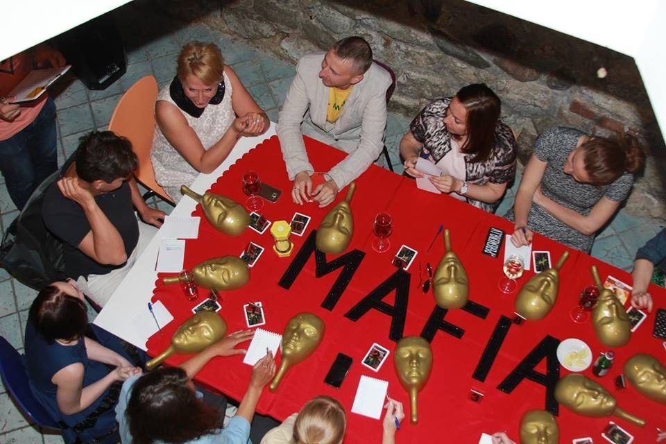 Sarkans galds ar uzrakstu MAFIA un zelta maskām